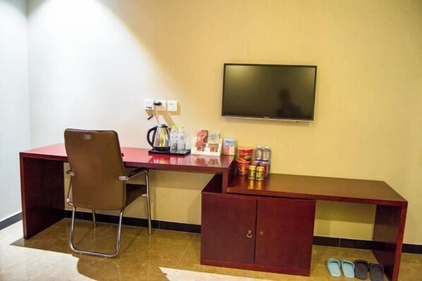 A room with a desk, chair, television, and a cabinet with shoes. - Bali Hotel (Cao County)