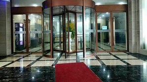 A lobby with a revolving door, a red carpet, and a checkered floor pattern.