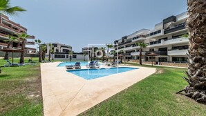 Un hotel moderno con piscina, palme e cielo sereno.