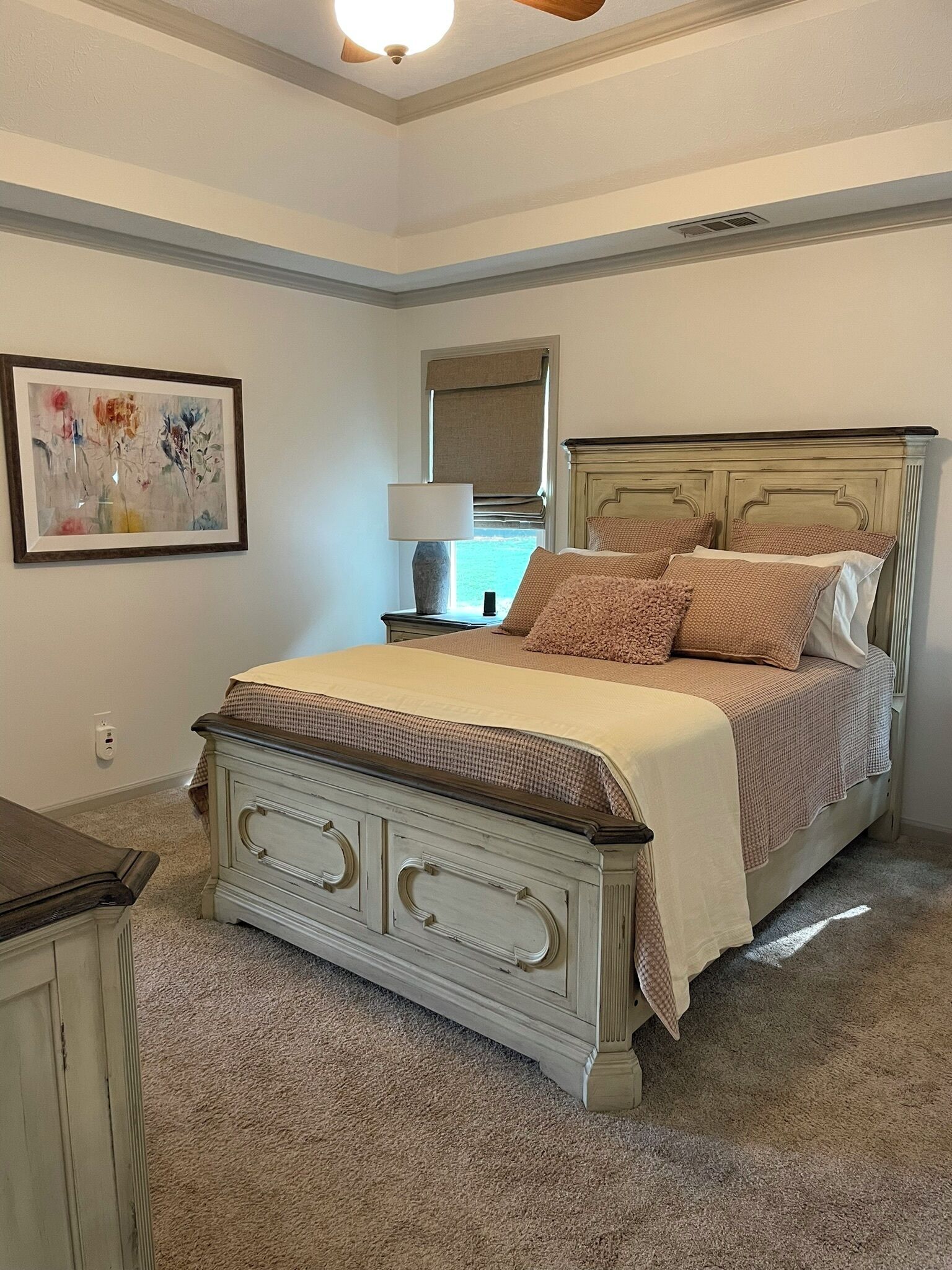 Une chambre à coucher avec un lit, une table de chevet, une lampe et un tableau encadré au mur.