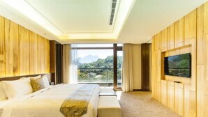 A hotel room with a large bed, a TV mounted on the wall, and a balcony with a view of the mountains. - Fuli Hot Spring Resort (Nantou)