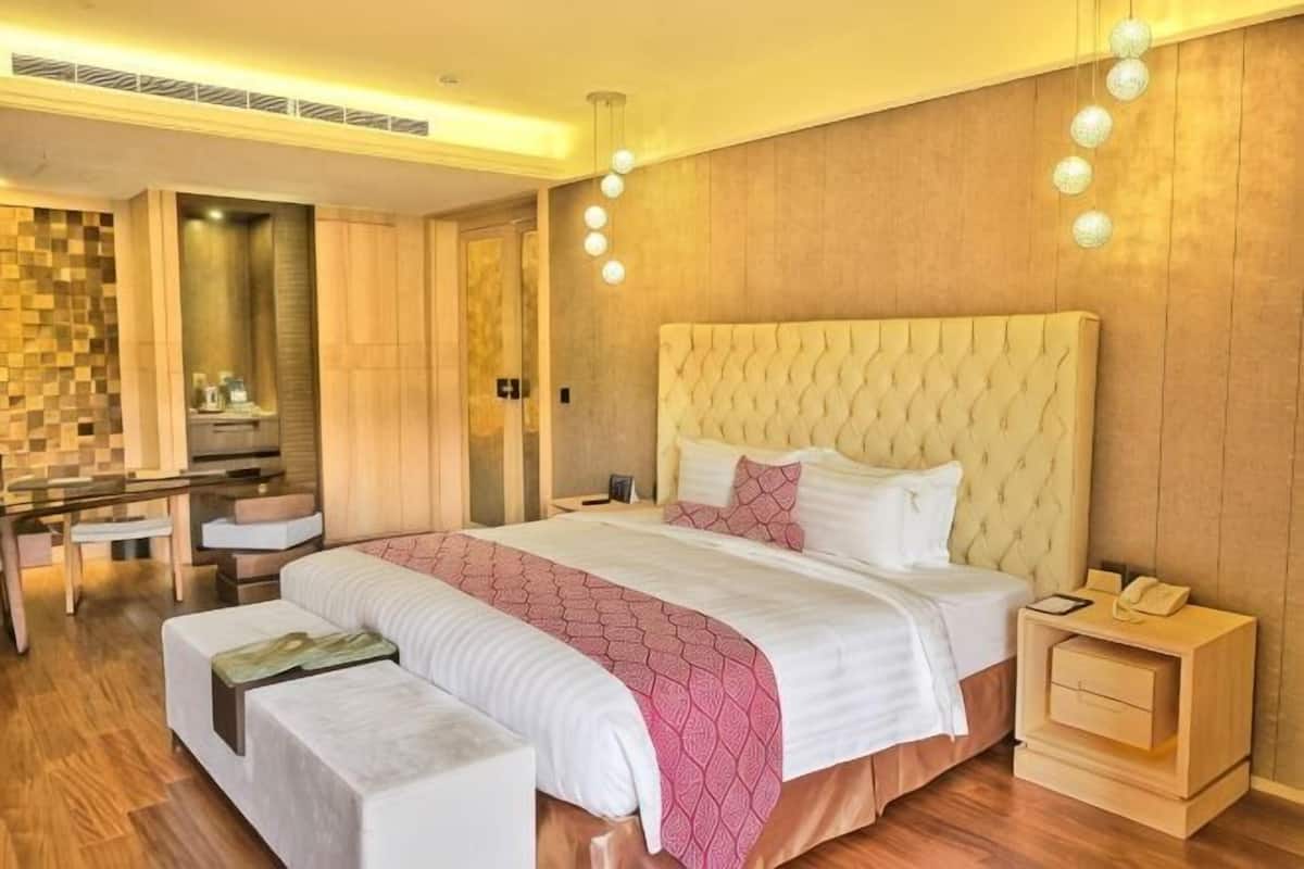 A modern hotel room with a large bed, bedside tables, a desk, and a mirror.