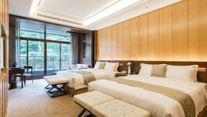 Una habitación de hotel con una cama grande, una cama más pequeña, un escritorio y un banco.
