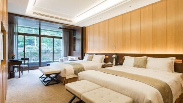 A hotel room with a large bed, a smaller bed, a desk, and a bench. - Fuli Hot Spring Resort (Nantou)