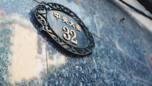 Placa de metal com o número 32 e caracteres chineses em superfície texturizada.