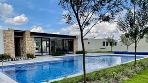 Ein modernes Haus mit Swimmingpool, einem gepflegten Rasen und blauem Himmel.