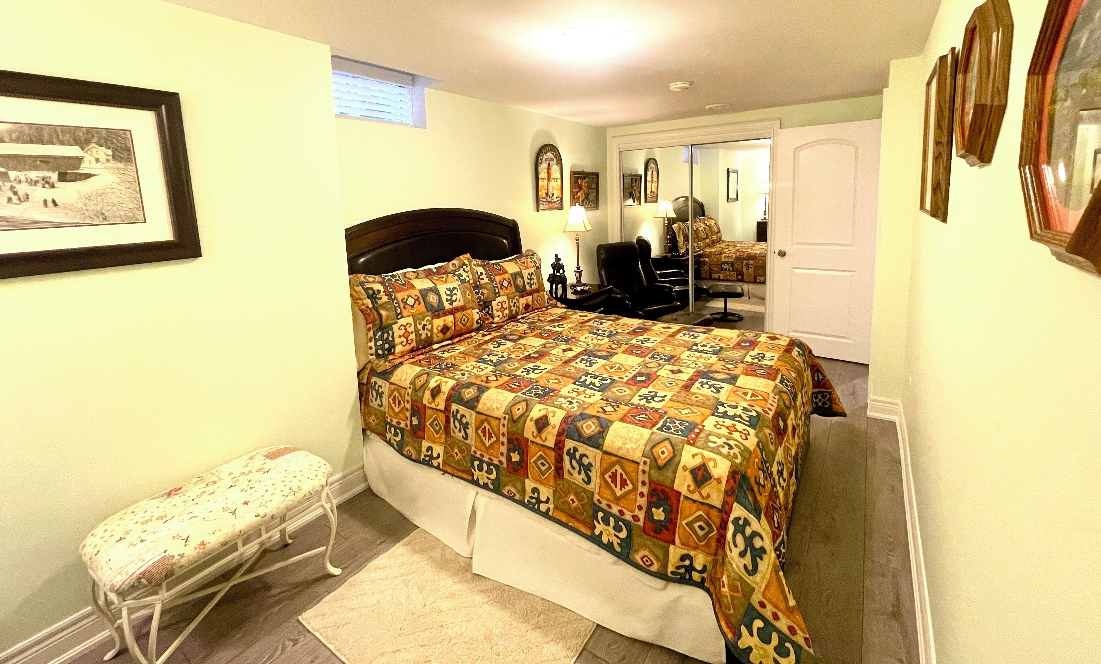 Un dormitorio con cama, una silla, un banco y una puerta.