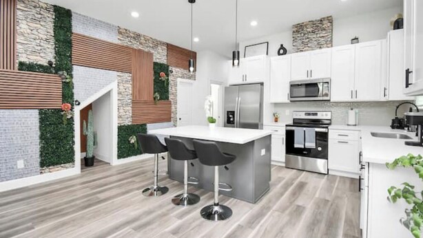 Una cocina moderna con una isla central, taburetes de bar y electrodomésticos integrados.