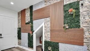 Un interior moderno con pared de piedra, listones de madera y follaje verde.