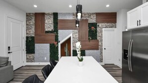 Una cocina moderna con encimera blanca, un refrigerador de acero inoxidable y una lámpara colgante.