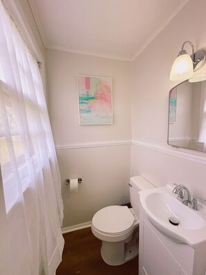 Ein Badezimmer mit Toilette, Waschbecken und einem Bild an der Wand.