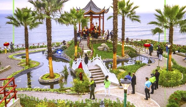 A landscaped garden with a gazebo, palm trees, and a water feature.