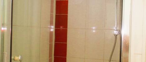A glass-enclosed shower stall with a red-tiled wall and a chrome showerhead.