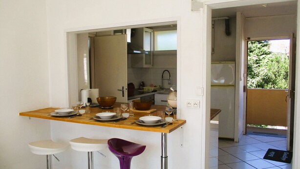 A compact kitchen with a dining area, including a bar stool and a small table set for two. - Limoges,, T2 ++parkings au Jardin ,,acces Facile ! (Limoges)
