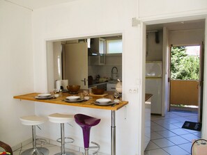 A compact kitchen with a dining area, including a bar stool and a small table set for two. - Limoges,, T2 ++parkings au Jardin ,,acces Facile ! (Limoges)