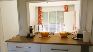 A kitchen with a wooden countertop, a coffee maker, a toaster, and a window with colorful curtains. - Limoges,, T2 ++parkings au Jardin ,,acces Facile ! (Limoges)