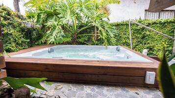 Un jacuzzi rodeado de exuberante follaje y suelo de piedra.
