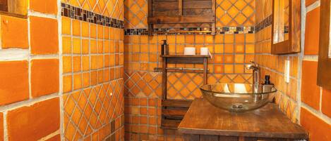 A bathroom with a tiled wall, a wooden vanity, a sink, and a mirror.
