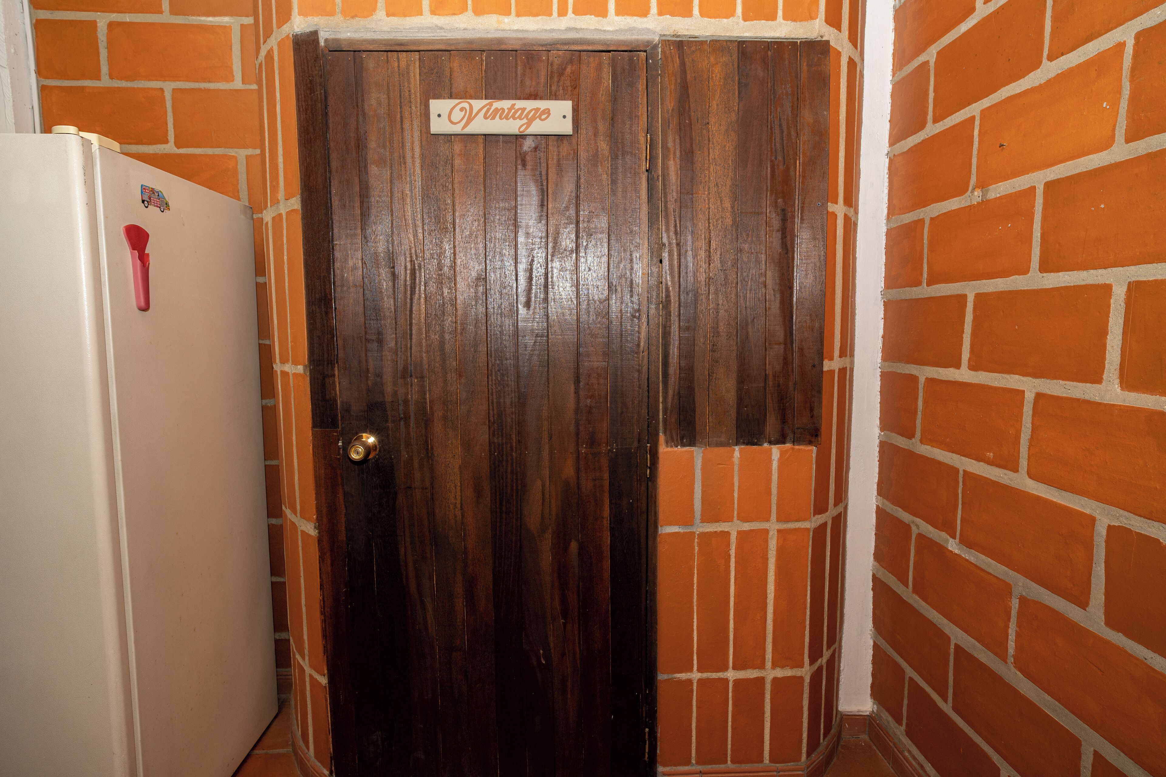 A door with a 'Vintage' sign, a refrigerator, and a brick wall.