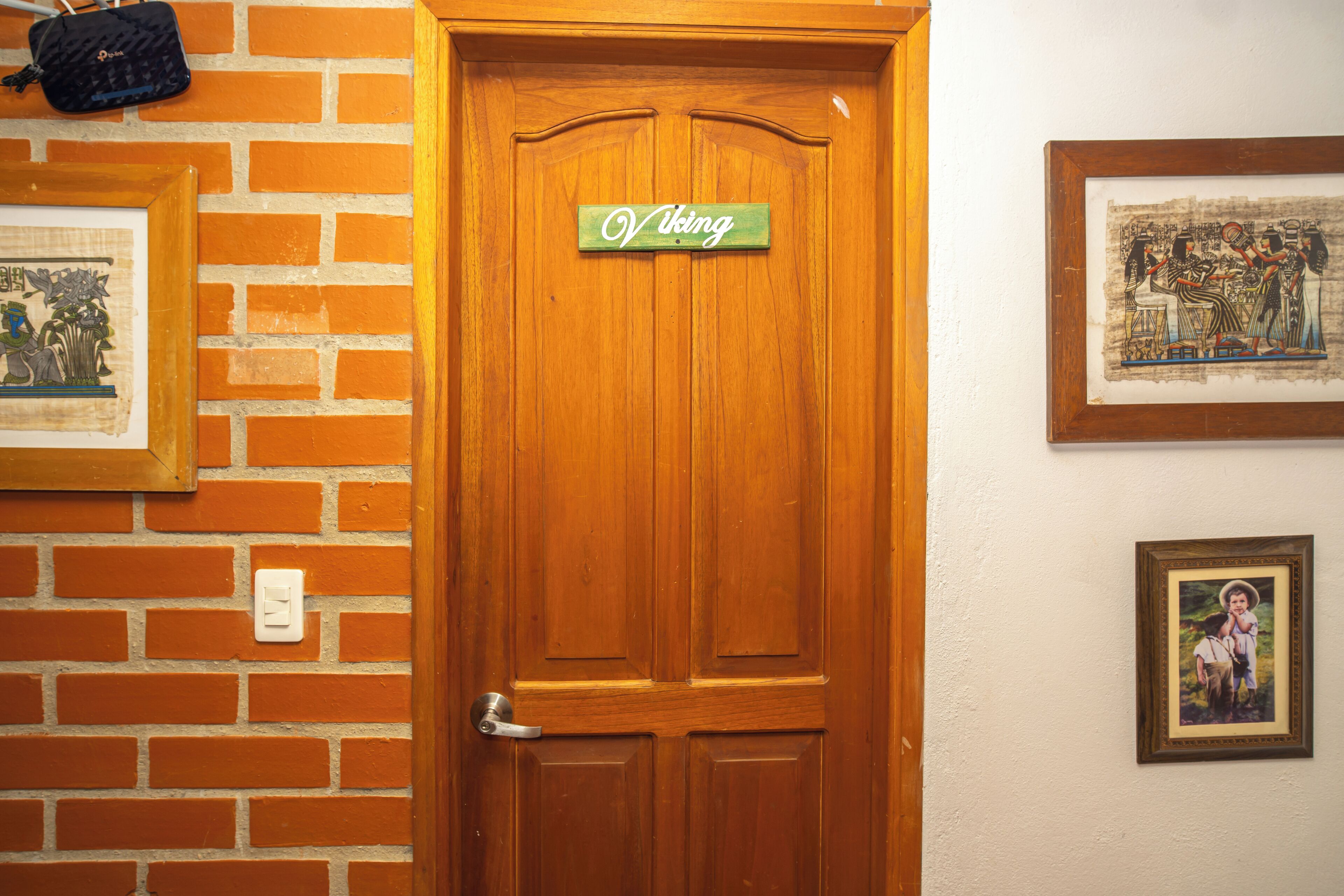 A wooden door with a sign reading 'Viking' above it, a framed picture on the wall to the left, and another framed picture to the right.
