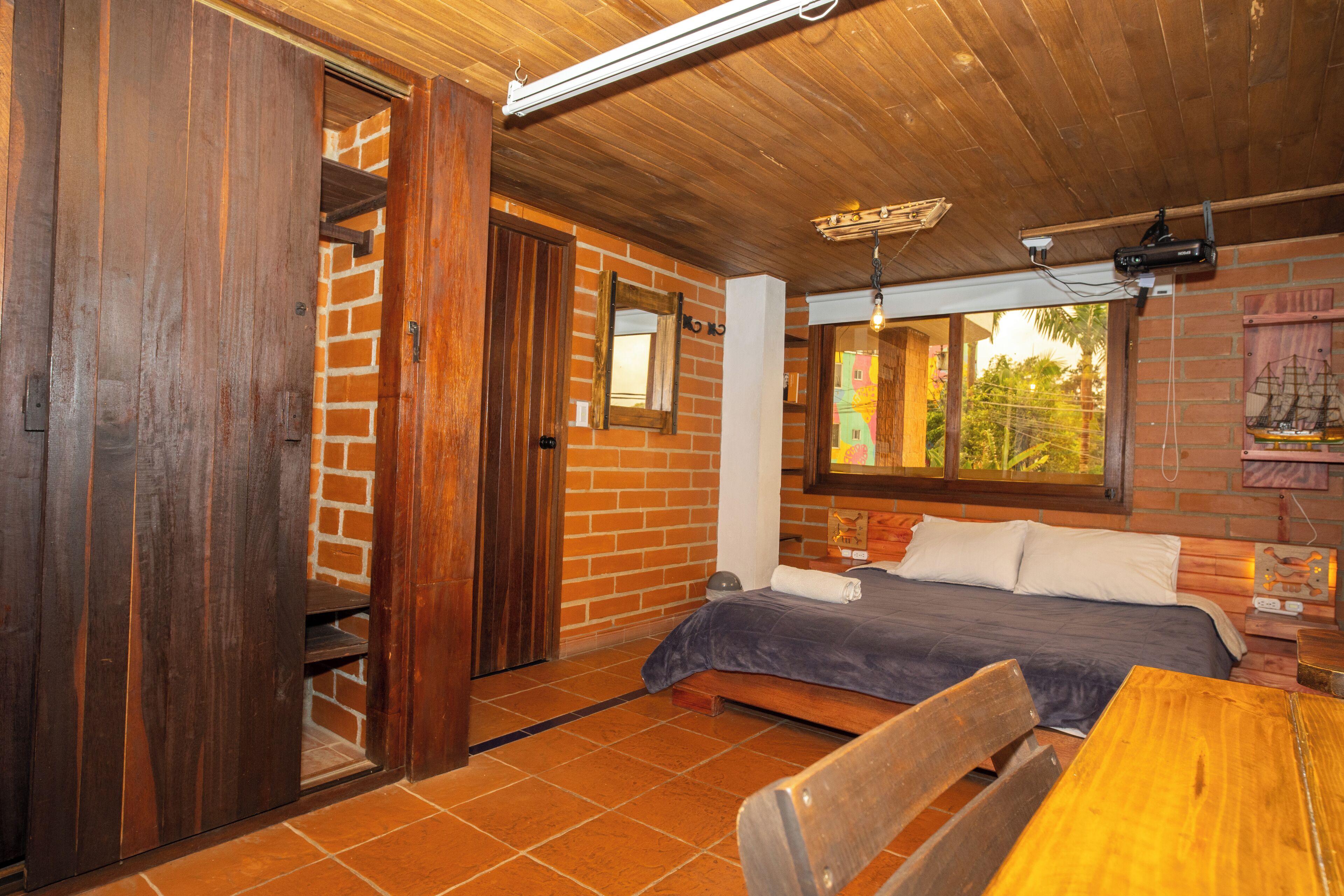 Ein Zimmer mit einem Bett, Holzmöbeln, einer Backsteinwand und einem Fenster.