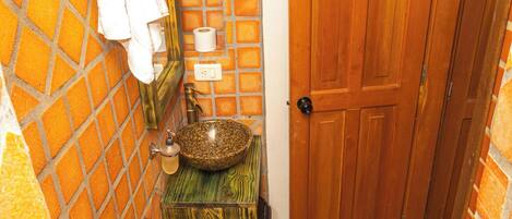 Un baño con puerta de madera, un lavabo, un espejo y una toalla colgada en la pared.