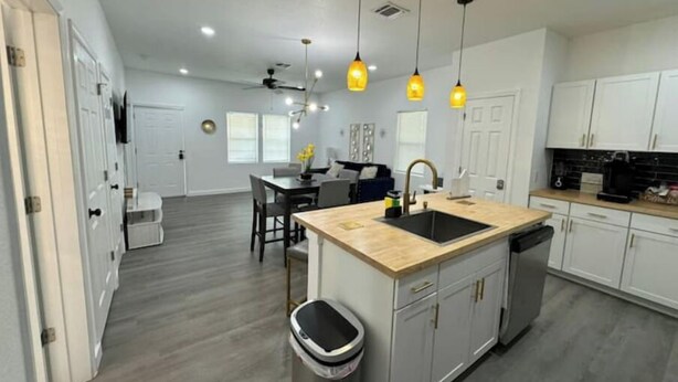 A modern kitchen with a central island, pendant lighting, and a view into the dining area. - Renovated home 5 min downtown
 (San Antonio)