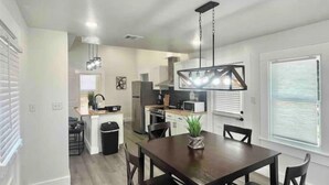 A modern kitchen with white cabinets, a central island, and a dining area with a wooden table and chairs.