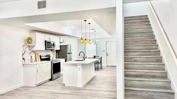 A modern kitchen with white cabinetry, a central island, and pendant lighting. - 6 min downtown New home (San Antonio)