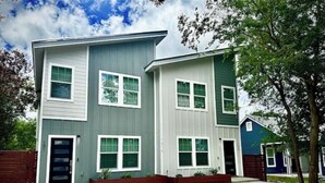 A modern two-story house with a grey and white exterior, multiple windows, and a front yard with a concrete driveway. - 6 min downtown New home (San Antonio)