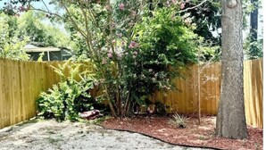 A backyard with a wooden fence, a tree, and various plants. - 6 min downtown New home (San Antonio)