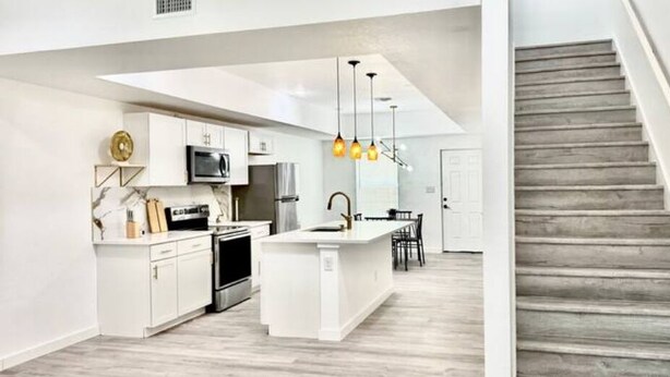 A modern kitchen with white cabinetry, a central island, and pendant lighting. - Brand new home 6 min downtown (San Antonio)