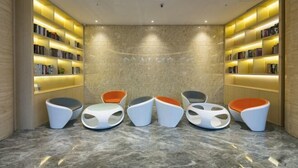 Un'area lettura moderna con sei sedie dal design originale e due librerie piene di libri.