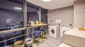 Una cucina moderna con un'ampia finestra, una lavatrice e un angolo bar con sgabelli.