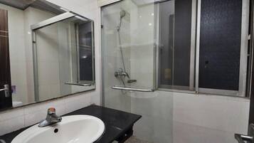 A bathroom with a sink, mirror, and glass-enclosed shower.