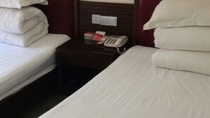A hotel room with two beds, a nightstand with a telephone, and a wall-mounted light switch. - Tianjiu Hotel (Cixi)