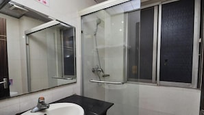 A bathroom with a white sink, a mirror, and a glass-enclosed shower area. - Tianjiu Hotel (Cixi)