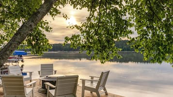 A wooden dock with chairs and tables overlooking a calm lake.