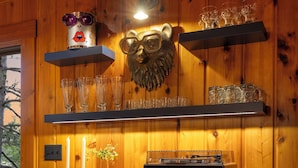 A wooden interior with a dark blue cabinet, shelves with glassware, a decorative animal head, and a record player.