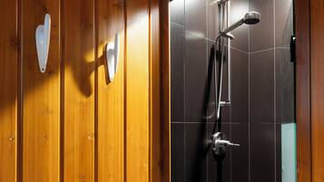 A wooden interior with a shower area featuring a black tiled wall and a metal shower head.