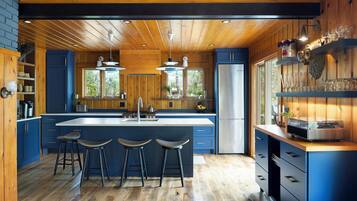 A modern kitchen with a central island, bar stools, and a large window.
