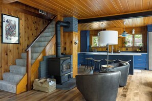 Una cocina moderna con una isla central, piso de madera y una escalera que sube a un altillo.