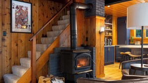 A cozy interior with a wooden staircase, a fireplace, and a kitchen area.