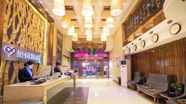 Un espace d’accueil d’hôtel avec un mur en bois, un comptoir de réception et un coin salon.