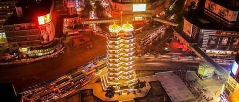 A multi-story building with a central tower, surrounded by a busy urban street at night.