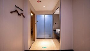 Une chambre d’hôtel dotée d’un placard à portes coulissantes, d’un porte-manteau en bois et d’une petite étagère.