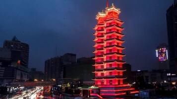 A multi-tiered pagoda-style building with a red-lit exterior, surrounded by a cityscape with visible traffic.