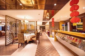 Un restaurant avec un sol à carreaux, un comptoir où sont exposées des bouteilles et un mur décoratif orné de motifs textuels.