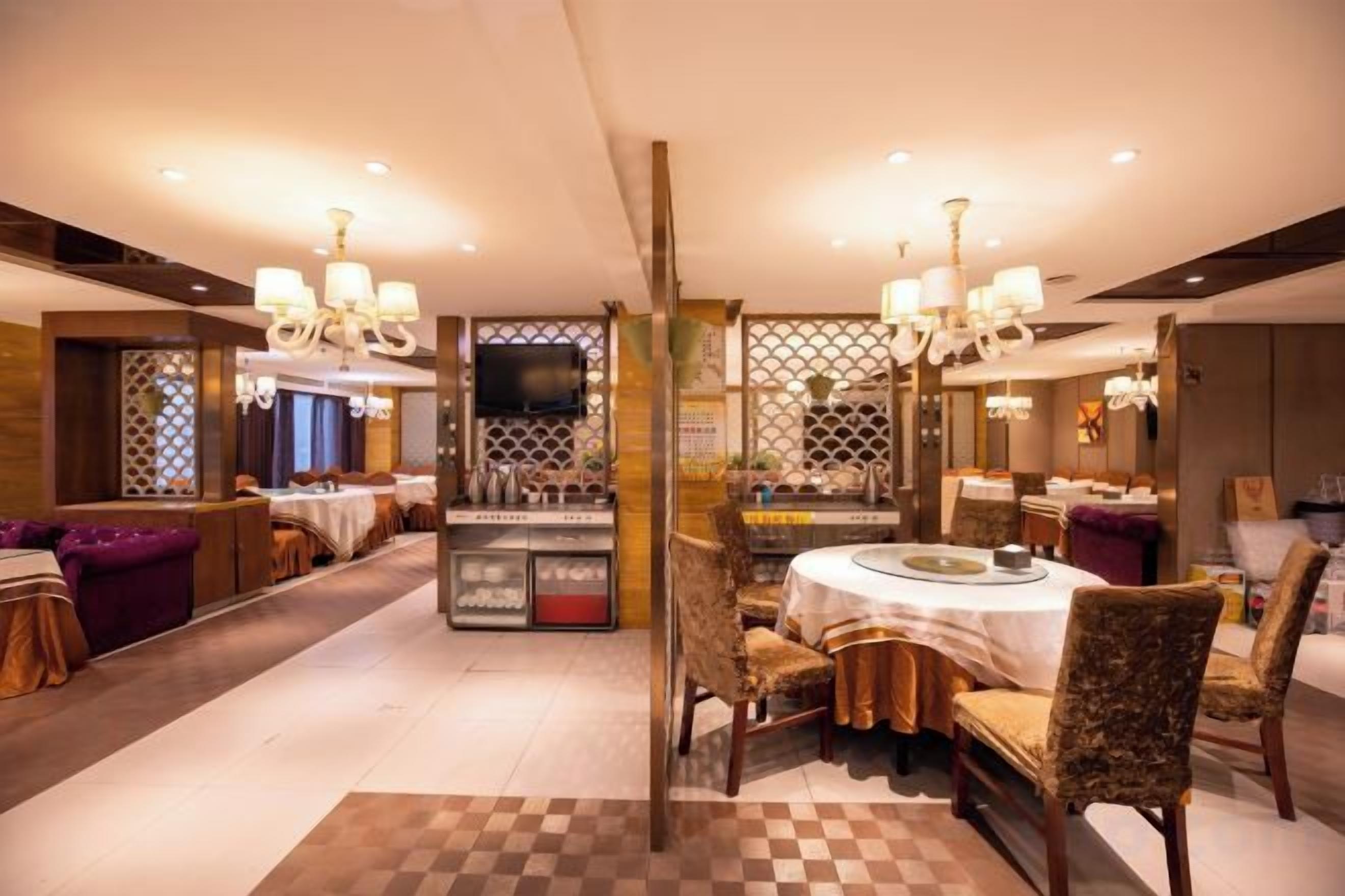 Een restaurantgedeelte in een hotel, met een ronde centrale tafel, diverse zithoeken en een schoteltjes vloer.