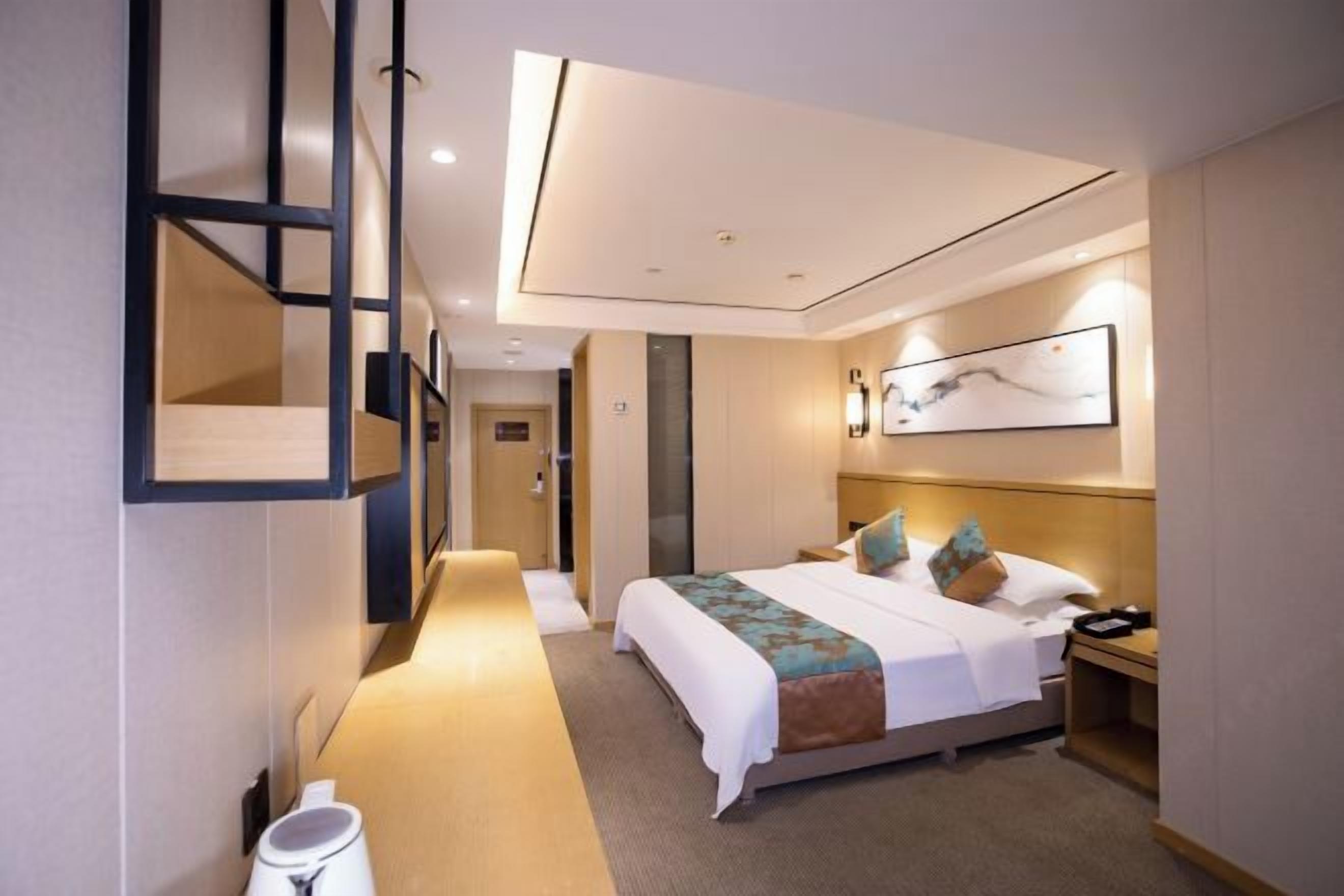 Una camera d'albergo con un letto, un comodino e un'opera d'arte appesa al muro.